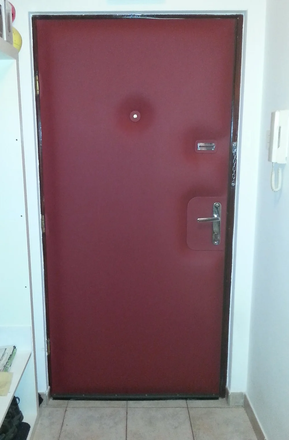 Bordo tapecirana ulazna vrata sa špijunkom i metalnim okovom.